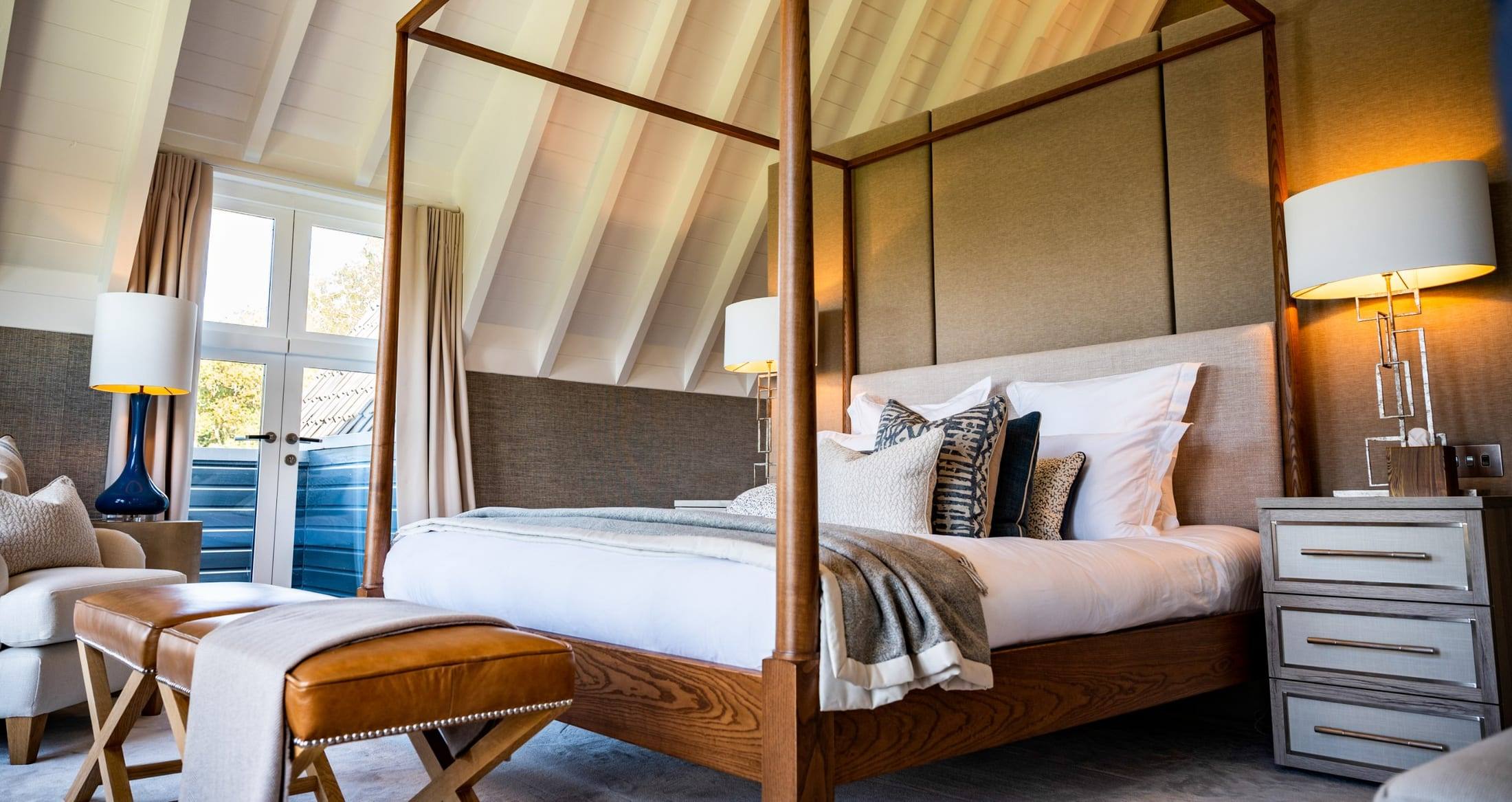 Master bedroom with a bespoke oak four-poster bed, tall upholstered headboard panels and fitted bedside chests