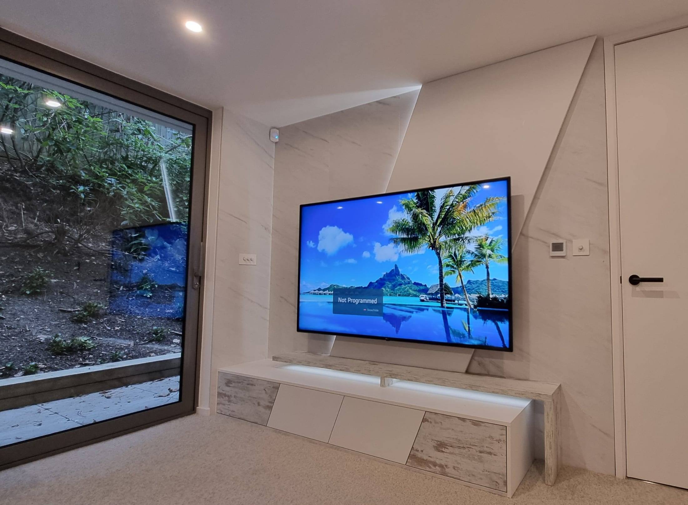 Angular marble-effect TV feature wall with hidden LED lighting and a floating TV unit